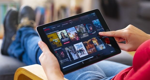 A person holding a tablet subscribed to Netflix